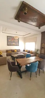 a living room with a wooden table and chairs at Villa 5 chambres targa in Marrakech