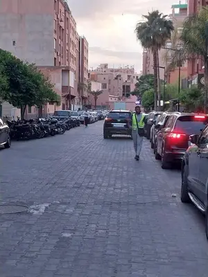 a person walking down a street with cars parked at Studio Confort au Cœur de Guéliz proche Carré Eden in Marrakech