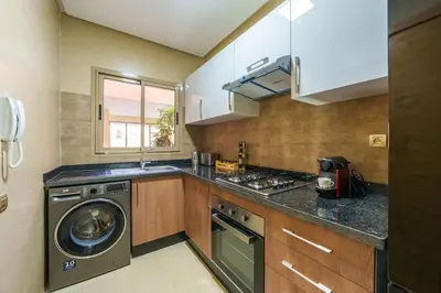 a kitchen with a stove and a washer and dryer at Vue Piscine et Golf Luxueux rez de jardin in Marrakech