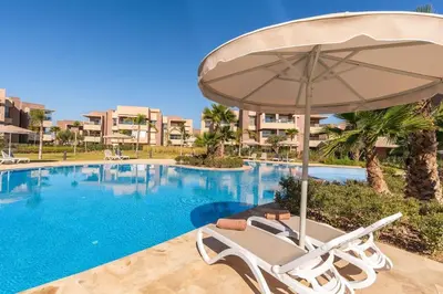 a chair and an umbrella next to a swimming pool at Vue Piscine et Golf Luxueux rez de jardin in Marrakech
