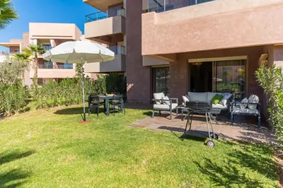 a patio with an umbrella and chairs and a table at Vue Piscine et Golf Luxueux rez de jardin in Marrakech