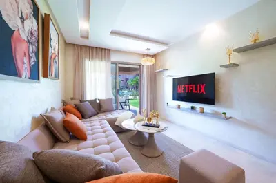 a living room with a couch and a tv at Vue Piscine et Golf Luxueux rez de jardin in Marrakech