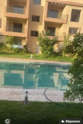 a swimming pool in front of a building at Appartement coralia in Marrakech