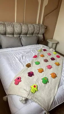 a bed with a blanket with colorful birds on it at Appartement coralia in Marrakech