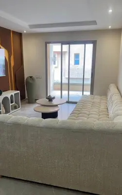 a large couch in a living room with a large window at Appartement coralia in Marrakech