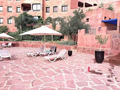 a group of chairs and umbrellas on a stone patio at L'ECRIN de la PALMERAIE in Dar Caïd Layadi