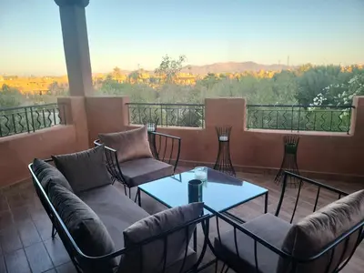 a balcony with couches and a table with a view at L'ECRIN de la PALMERAIE in Dar Caïd Layadi
