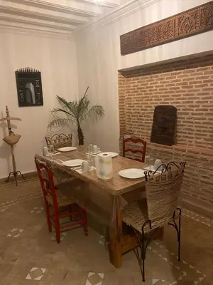 a dining room table with chairs and a brick wall at Riad khalid zrika in Marrakech