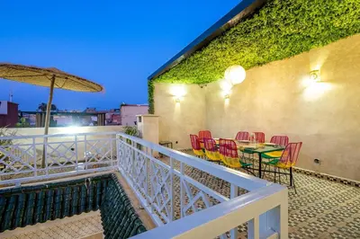 a balcony with a table and chairs and an umbrella at Riad Ryme-Newly renovated-Exclusive-Free breakfast in Marrakech
