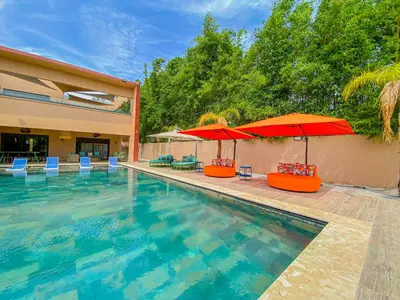 a swimming pool with two umbrellas and some chairs and tables at villas route d amzmiz in Marrakech