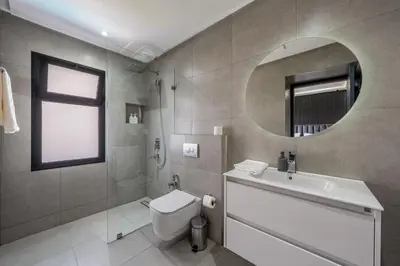 a bathroom with a toilet and a sink and a mirror at Villa Arbia - Piscine - 5BDR - Fitness - Ping-Pong in Sraghna