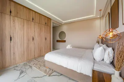a bedroom with a large bed and wooden cabinets at Villa Arbia - Piscine - 5BDR - Fitness - Ping-Pong in Sraghna