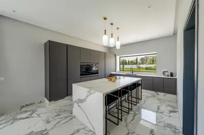 a kitchen with marble flooring and a large island at Villa Arbia - Piscine - 5BDR - Fitness - Ping-Pong in Sraghna