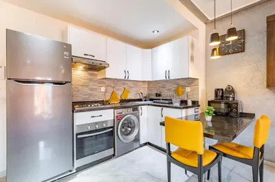a kitchen with a refrigerator and a table and chairs at Luxury CINÉMA-BEDROOM AK38 FullHD Guéliz-TopCenter in Marrakech