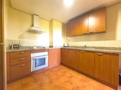 a kitchen with wooden cabinets and a white appliance at Majorelle Apartment - Terrace Stunning Garden View in Marrakech