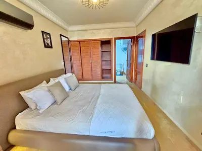 a bedroom with a large white bed with a television at Joli et chic Appartement à Marrakech - balcon privé et confort in Oulad Akkou