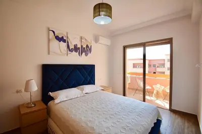 a bedroom with a large bed and a balcony at Appartement calme et ensoleillé avec piscine in Marrakech