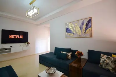 a living room with a blue couch and a tv at Appartement calme et ensoleillé avec piscine in Marrakech