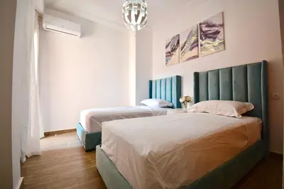 a bedroom with two beds and a chandelier at Appartement calme et ensoleillé avec piscine in Marrakech
