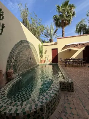 a swimming pool with a tiled floor and a house at Luxury Private Riad, Air-Conditioned and Pool in Marrakech