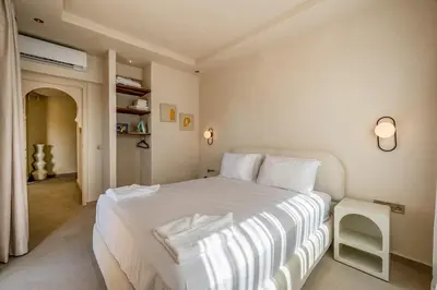 a bedroom with a large white bed with a table at Pearl of Guéliz Netflix, Terrace, Quiet in Marrakech