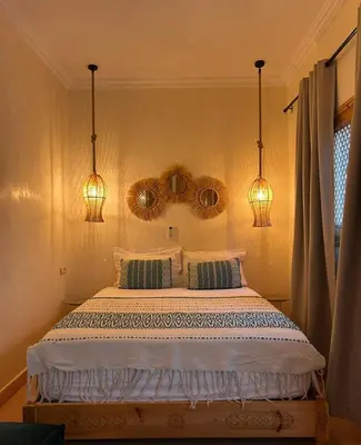a bedroom with a bed with two pillows and two lights at Riad Privatisé- Riad Dar Farida in Marrakech