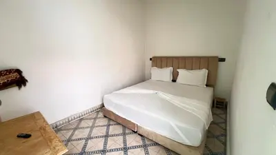 a small bedroom with a bed with white sheets at Riad Nomad in Marrakech