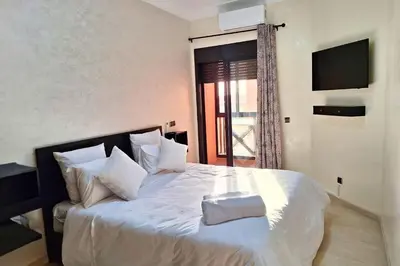 a bedroom with a large white bed with a window at Luxe et sérénité avec jardin, terrasse et 5 piscines in Marrakech