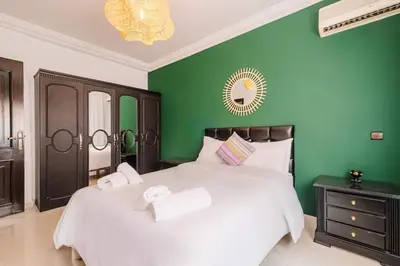 a bedroom with green walls and a bed with two towels at Central Marrakech Apartment 2 Bedrooms Next to Majorelle Garden in Marrakech