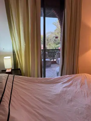 a bedroom with a bed and a view of a patio at Luxury apartement Palmeraie Village in Marrakech