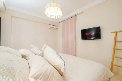 a bedroom with a bed with white pillows and a tv at Charmant appartement lumineux pres de Gueliz. in Marrakech