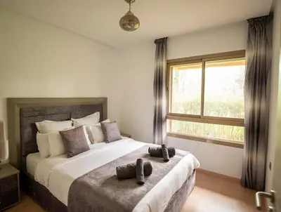 a bedroom with a large bed with a large window at Modern 3BR Apartment with Pool & Golf Views in Marrakech