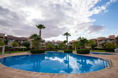 a large swimming pool with palm trees and buildings at Modern 3BR Apartment with Pool & Golf Views in Marrakech