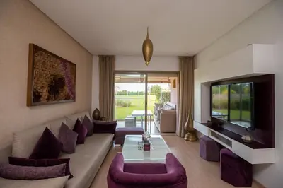 a living room with a couch and a tv at Modern 3BR Apartment with Pool & Golf Views in Marrakech