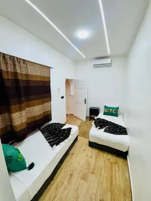 two beds in a room with white walls and wooden floors at Maison N 07 in Marrakech