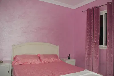 a bedroom with pink walls and a bed with pink sheets at apartment,5 min to airport, In a quiet place in Marrakech