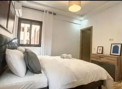 a bedroom with a bed with white sheets and a window at Apartments giliz Marrakech in Marrakech