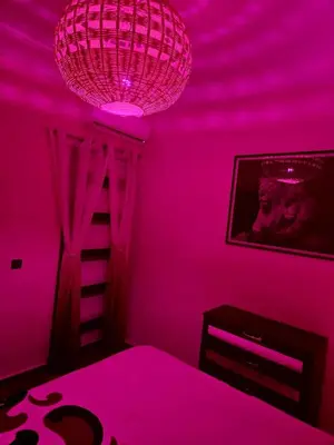 a pink bedroom with a chandelier and a tv at Au cœur de l orient Marrakech in Marrakech