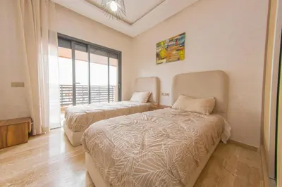 a bedroom with two beds and a large window at Appartement Plaza Madani in Marrakech