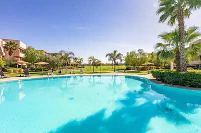 a large swimming pool in a resort with palm trees at Spacious Apartment, Golf & Pool in Marrakech
