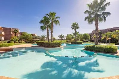 a swimming pool with palm trees in a resort at Spacious Apartment, Golf & Pool in Marrakech