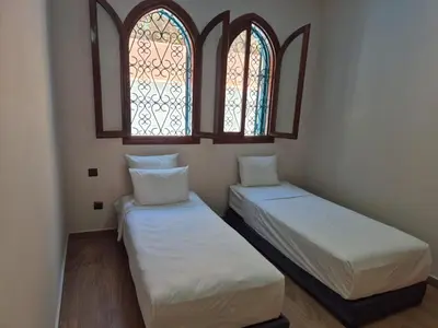 two beds in a room with two windows at Villa Kaina in Marrakech