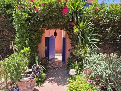 an entrance to a garden with flowers and a blue door at Villa Kaina in Marrakech