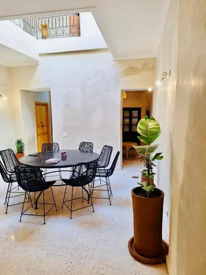 a table and chairs in a room with a potted plant at Dar Tiegezh in Marrakech