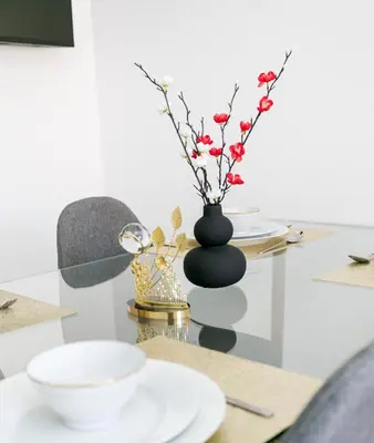 a table with a black vase with flowers in it at Pearl of Nour Prestige in Marrakech