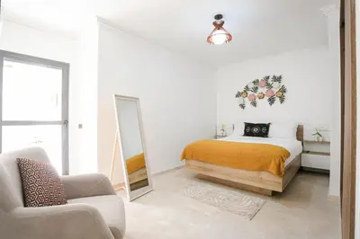 a bedroom with a bed and a mirror and a chair at Pearl of Nour Prestige in Marrakech
