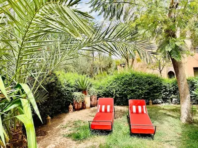 two red chairs sitting in the grass next to a tree at Le Palmito - 2BDR - Private Garden - Pool in Marrakech