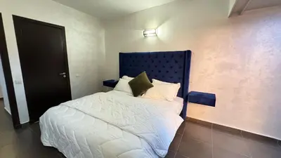 a bed with a blue headboard in a room at Apartment Ghita Cozy Stay in Central Marrakech in Marrakech
