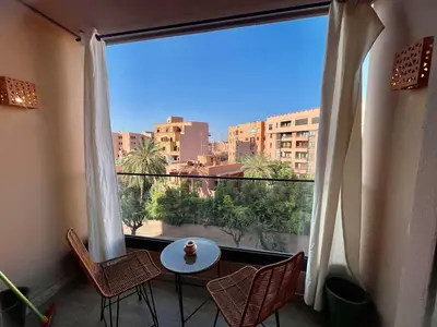 a balcony with a table and chairs and a large window at Modern Oasis in Gueliz - Balcony & Comfort in Marrakech