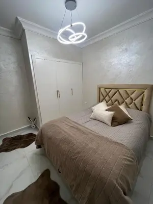 a bedroom with a large bed and a chandelier at Appartement Cosy Marrakech in Marrakech